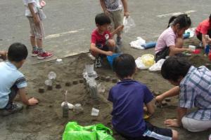 写真：子どもたちが、砂場での造形遊びをしている様子
